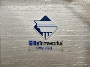 White brick wall panels set behind the Elite Trimworks logo