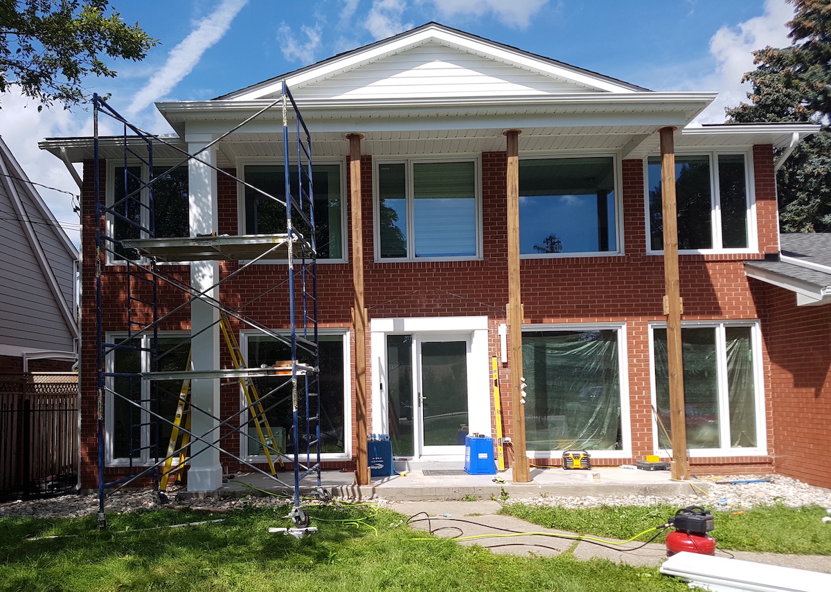 Tall plain PVC column wraps being installed outside home