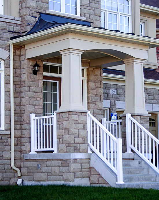 Painted tapered pvc column wraps on stone pedestals bordering the front porch